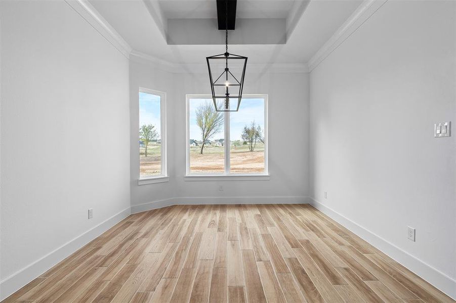 Empty room featuring beam ceiling, a notable chandelier, crown molding, and light wood-type flooring