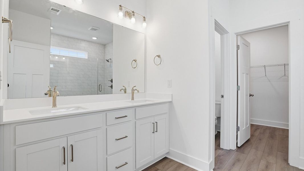 Highly functional and elegant en-suite with dual vanities, tiled walk-in shower, and refined finishes