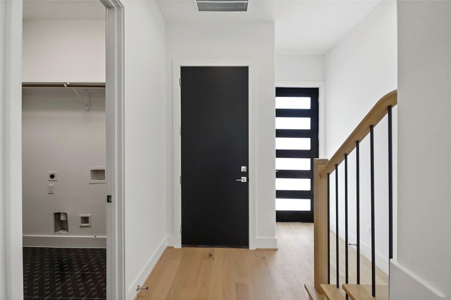 A sleek entryway with a convenient coat closet and striking modern staircase, enhanced by a practical laundry nook. A sleek entryway with a convenient coat closet and striking modern staircase, enhanced by a practical laundry nook.