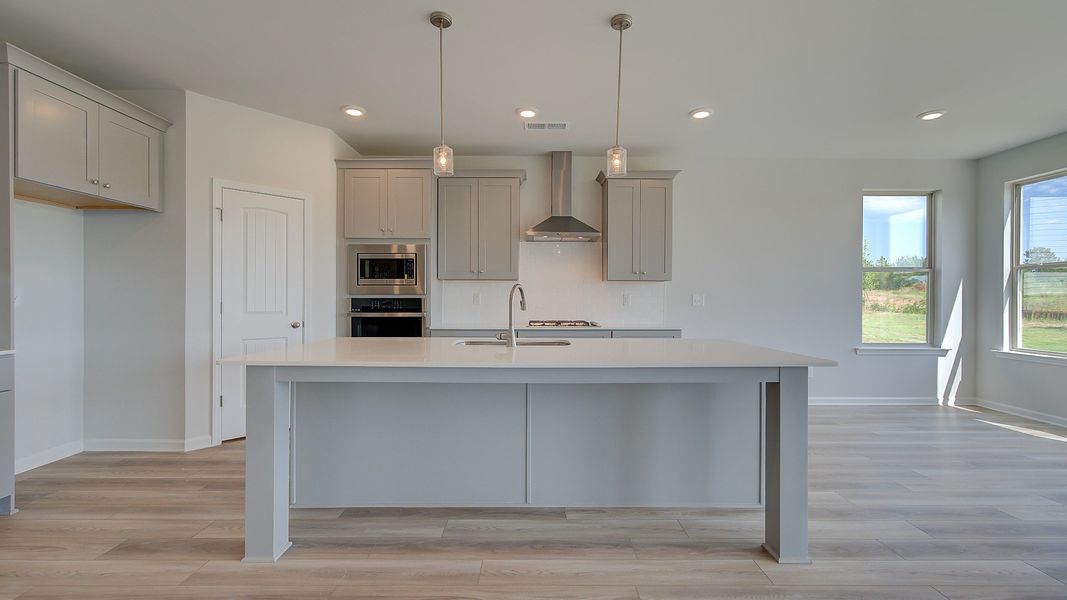 Clarity open-concept family room with LVP flooring and view of kitchen and breakfast area at Brighton in Locust Grove, GA.