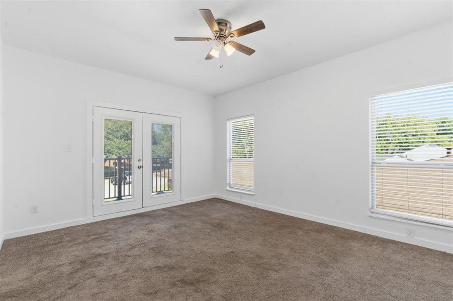 Carpeted spare room featuring healthy amount of natural light, french doors, and ceiling fan Carpeted spare room featuring healthy amount of natural light, french doors, and ceiling fan