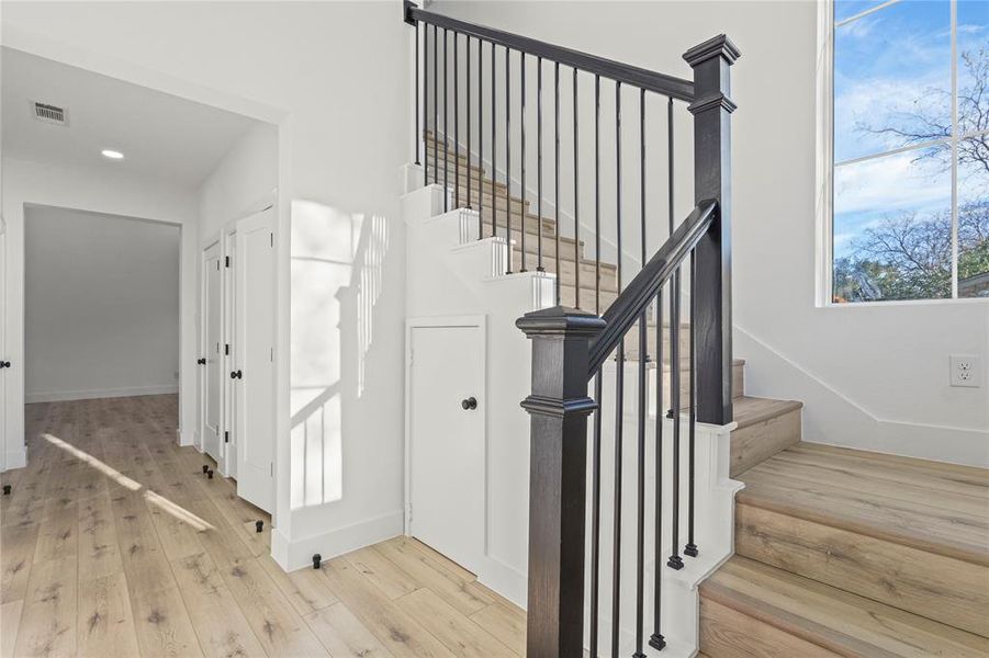 Staircase with wood finished floors and plenty of natural light