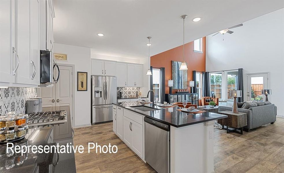 Kitchen featuring white cabinets, appliances with stainless steel finishes, hardwood / wood-style floors, and an island with sink