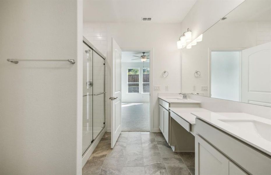 Elegant owner's suite with dual vanity and oversized shower*real home pictured