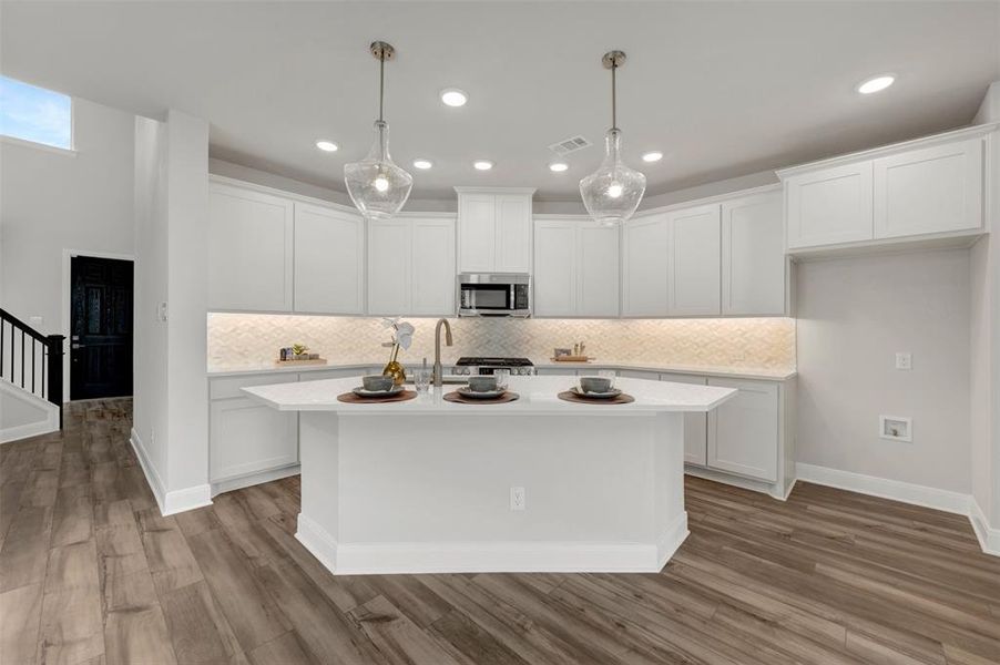 Contemporary kitchen featuring a hexagonal island with a light-colored countertop, white shaker cabinetry, stainless steel appliances, and a patterned backsplash