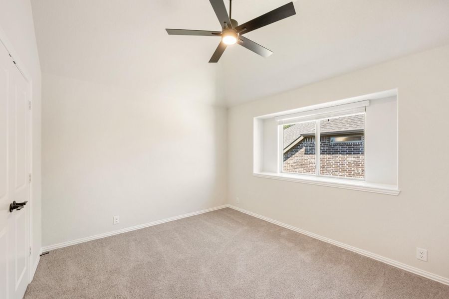 Empty bedroom with carpet flooring, ceiling fan, and a single window with white trim Empty bedroom with carpet flooring, ceiling fan, and a single window with white trim