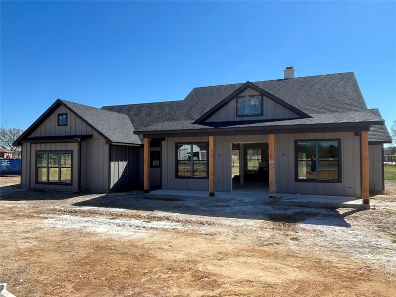 View of front of house featuring covered porch, roof with shingles, a chimney, and board and batten siding