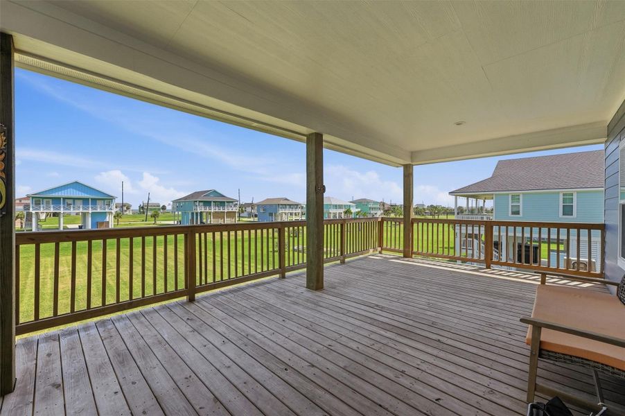 Spacious covered deck with wooden flooring offers serene views of charming coastal homes and lush green lawns, ideal for relaxation or entertaining. Spacious covered deck with wooden flooring offers serene views of charming coastal homes and lush green lawns, ideal for relaxation or entertaining.
