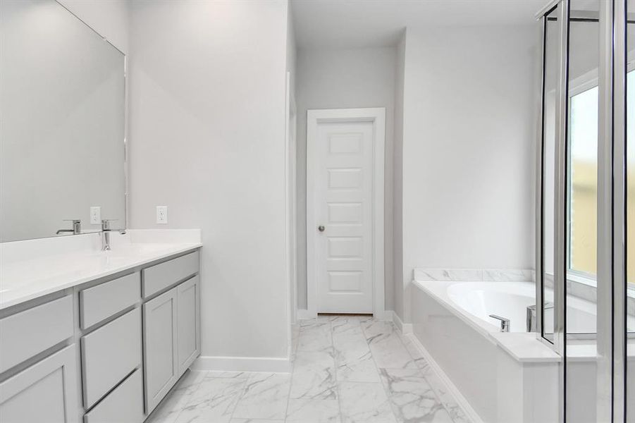 The primary en-suite has a soaking tub to give you that spa experience. The large privacy window allow lots of nature light in the space. Sample photo of completed home with same plan. Actual colors and selections may vary.