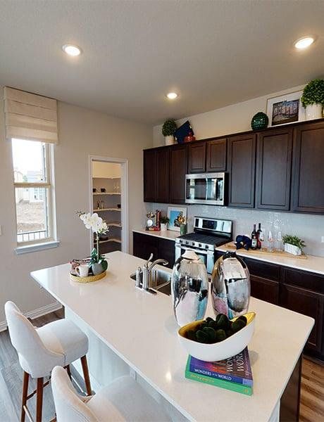 Kitchen featuring light wood-type flooring, dark wood finish cabinetry, stainless steel appliances, a kitchen breakfast bar, and a kitchen island with sink