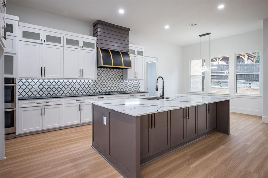 Gorgeous Kitchen with 6 burner gas cooktop, double over, microwave, and custom painted black stainless steel vent hood.