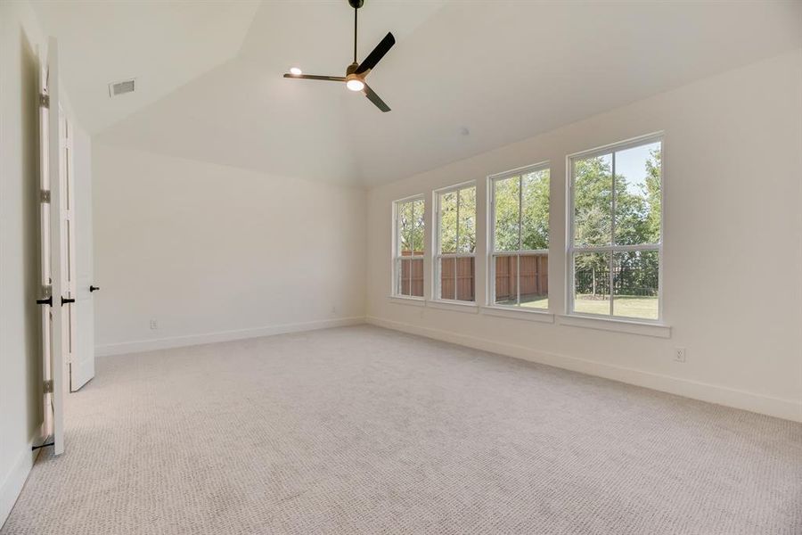 Empty room featuring light colored carpet, a ceiling fan, and high vaulted ceiling Empty room featuring light colored carpet, a ceiling fan, and high vaulted ceiling
