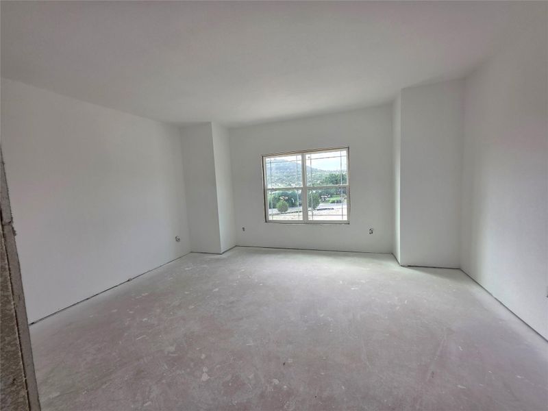 Spacious room featuring a large window, white painted walls, and an unfinished concrete floor