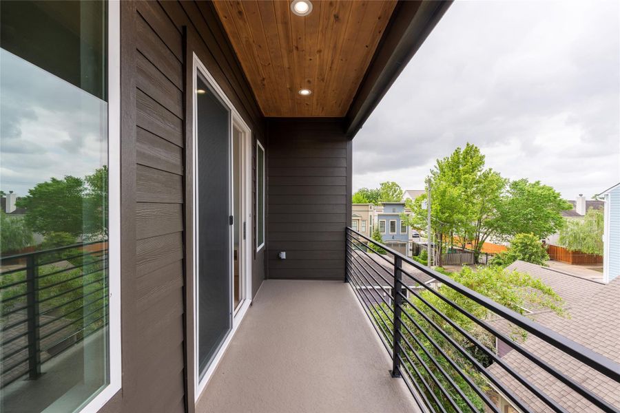 A private pocket of outdoors attached to the primary suite. The cedar ceiling warms the space at dusk, the railing keeps the sightline open to the canopy, and the door slides back in a single motion when you need the weather to do the talking.