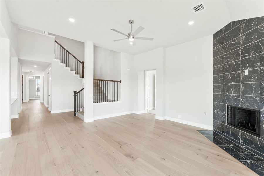 Open living room with hardwood floors, dark marble fireplace, staircase, and ceiling fan Open living room with hardwood floors, dark marble fireplace, staircase, and ceiling fan