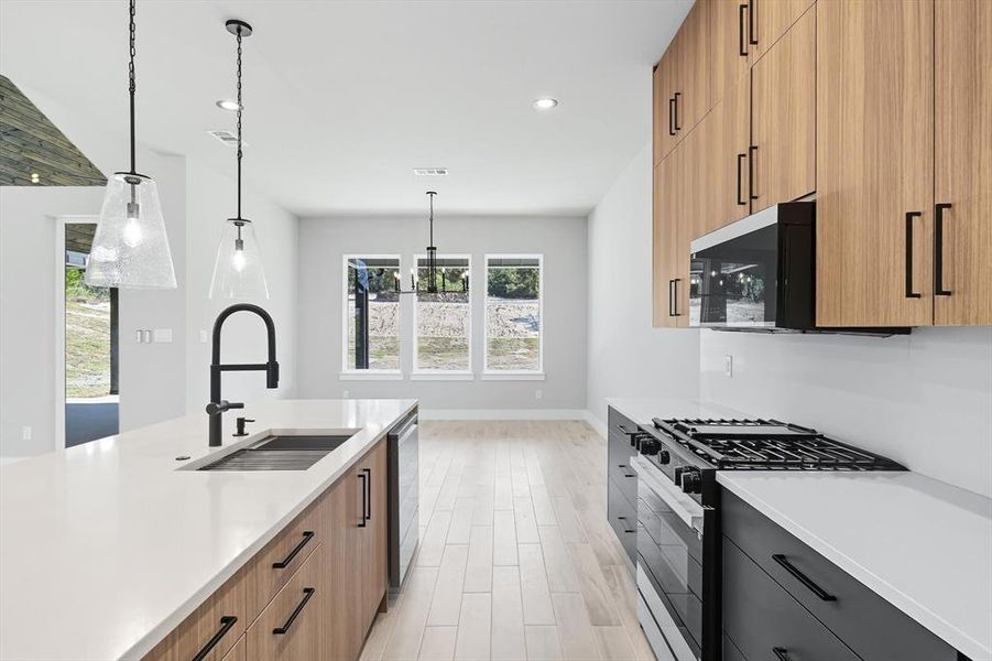 Kitchen with gas range, modern cabinets, pendant lighting, light wood-type flooring, and recessed lighting Kitchen with gas range, modern cabinets, pendant lighting, light wood-type flooring, and recessed lighting