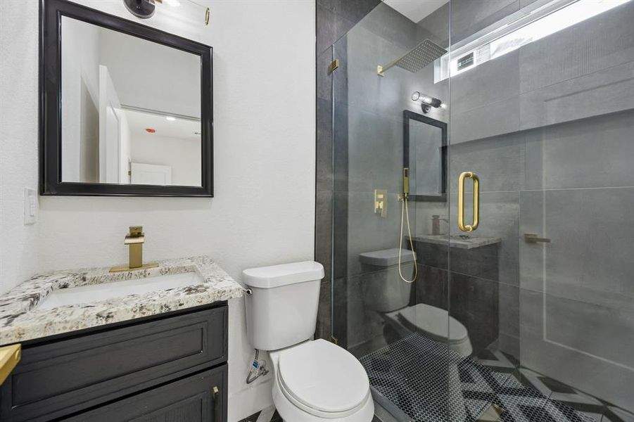 Contemporary bathroom featuring a glass-enclosed shower with gold-finish fixtures and a patterned tile floor Contemporary bathroom featuring a glass-enclosed shower with gold-finish fixtures and a patterned tile floor