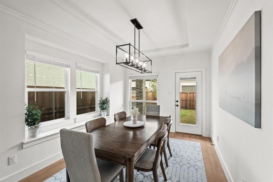 Dining space with plenty of natural light, light wood-style floors, a chandelier, and crown molding Dining space with plenty of natural light, light wood-style floors, a chandelier, and crown molding