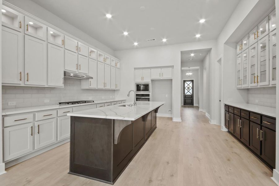 Kitchen featuring under cabinet range hood, a sink, light wood-type flooring, built in microwave, and gas stovetop Kitchen featuring under cabinet range hood, a sink, light wood-type flooring, built in microwave, and gas stovetop