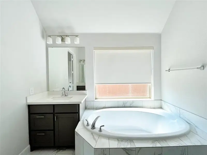 Bathroom featuring vanity and a bath Bathroom featuring vanity and a bath