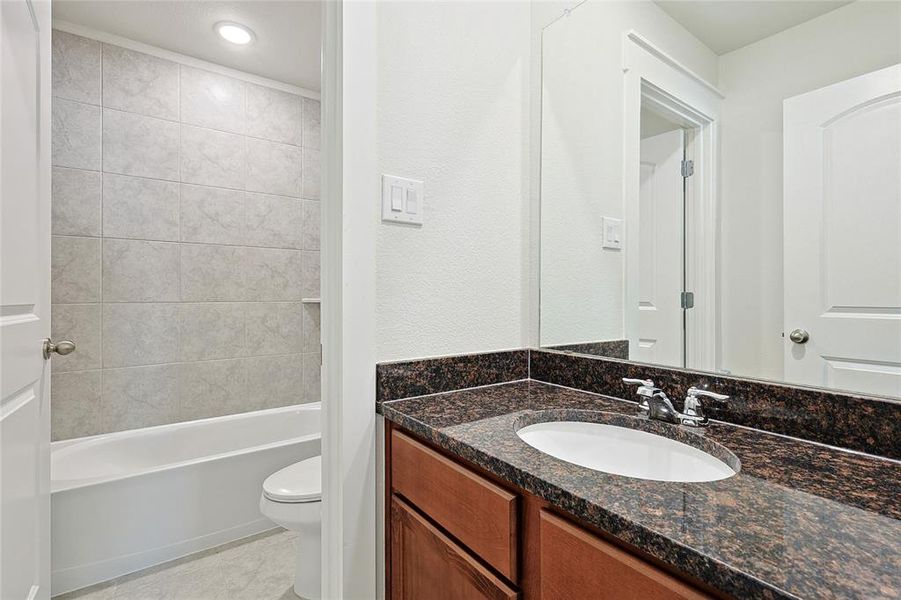 Full bathroom with tile patterned flooring, vanity, toilet, and tiled shower / bath