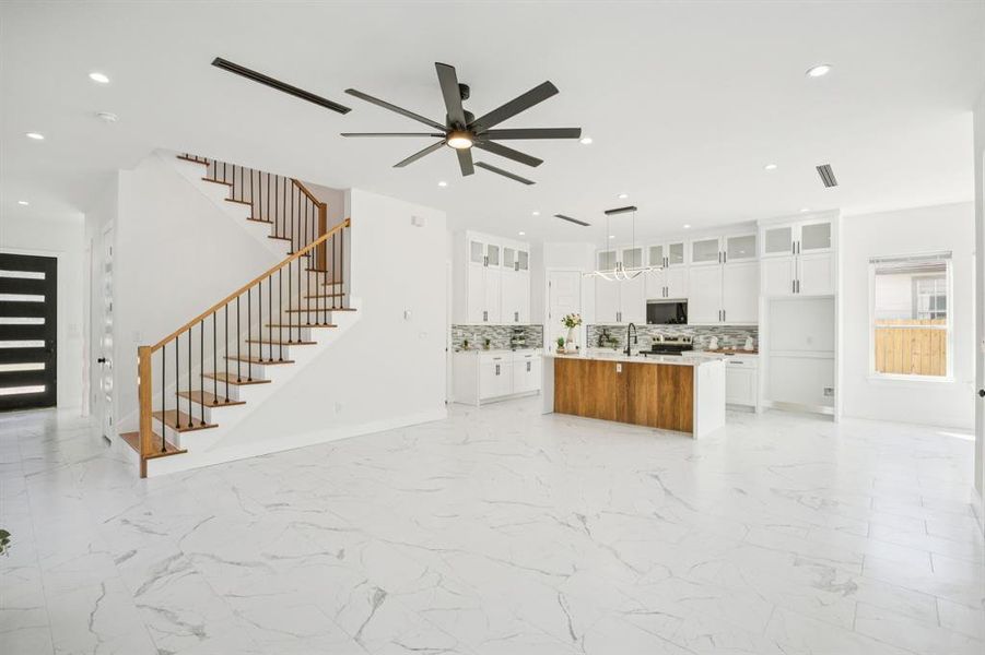 Unfurnished living room featuring stairway, light marble finish floors, recessed lighting, and ceiling fan