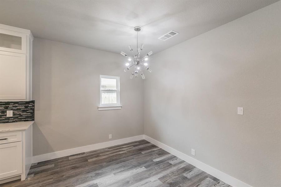 Unfurnished dining area with wood-type flooring and an inviting chandelier