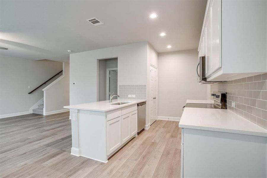 Kitchen with stainless steel appliances, a peninsula, visible vents, and white cabinets