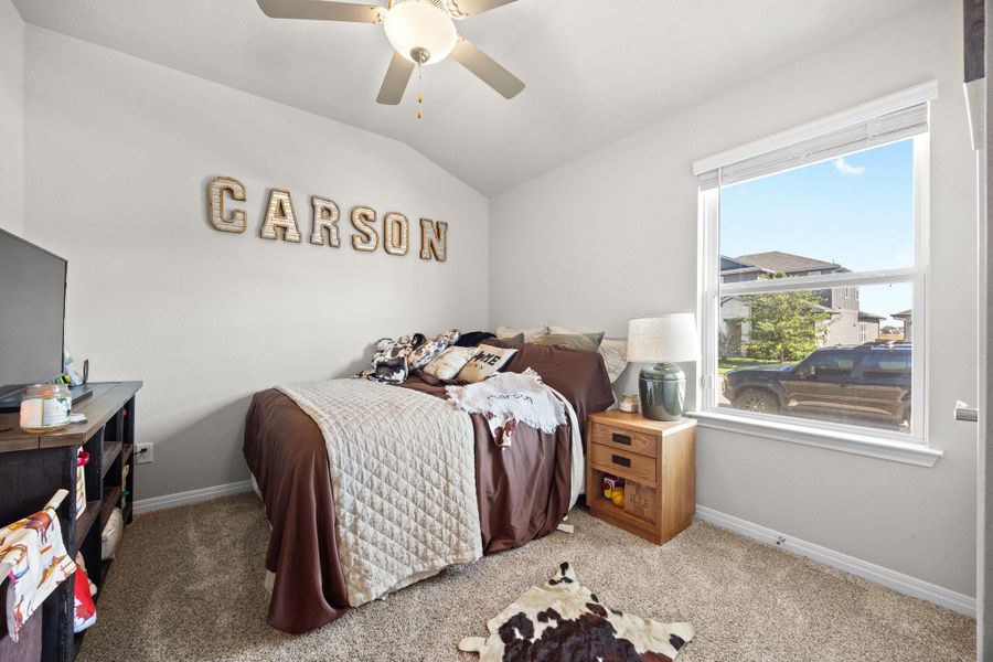 Bedroom with carpet flooring, vaulted ceiling, and a ceiling fan Bedroom with carpet flooring, vaulted ceiling, and a ceiling fan