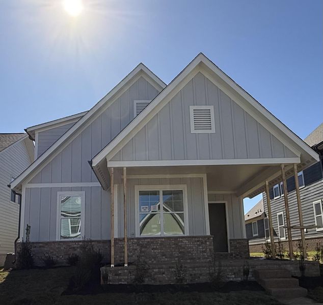 View of front of home with board and batten siding, a porch, and brick siding