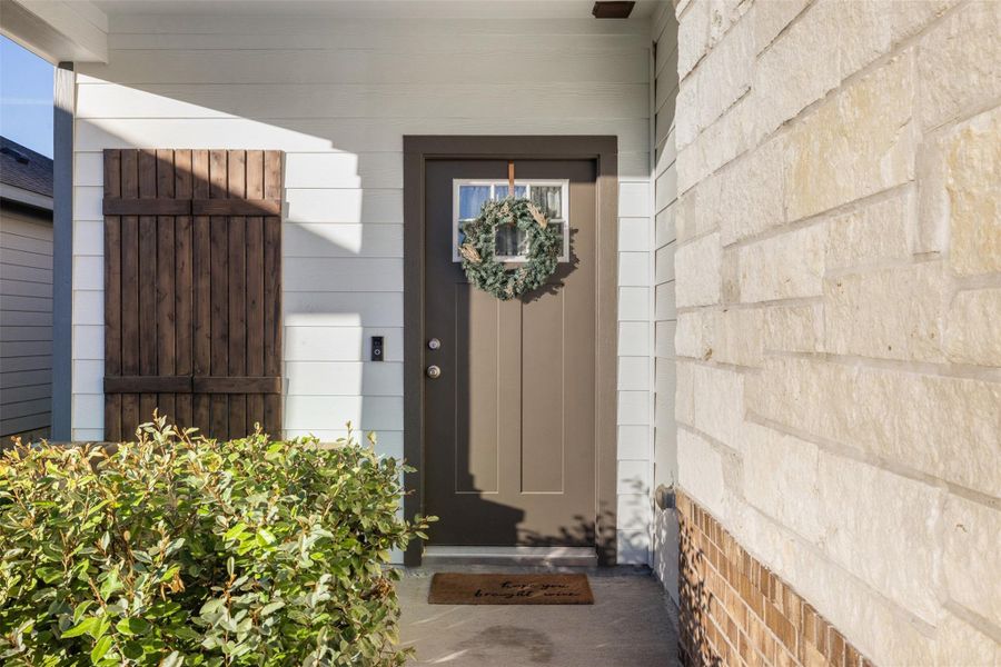 Charming entryway featuring a stone facade and wooden shutters, creating a welcoming and rustic feel.