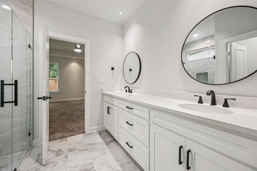 Full bathroom featuring double vanity, marble look tiles, a stall shower, and recessed lighting Full bathroom featuring double vanity, marble look tiles, a stall shower, and recessed lighting