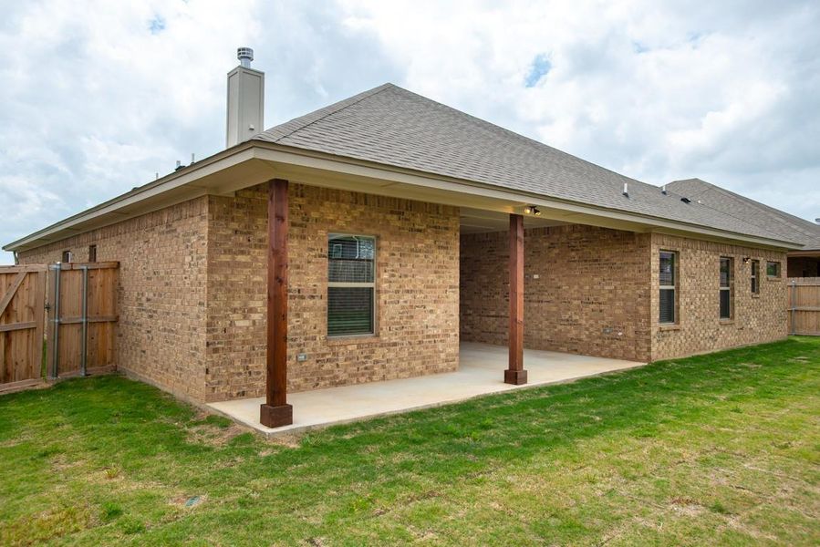 Rear view of house with fence, a yard, a patio area, and brick siding