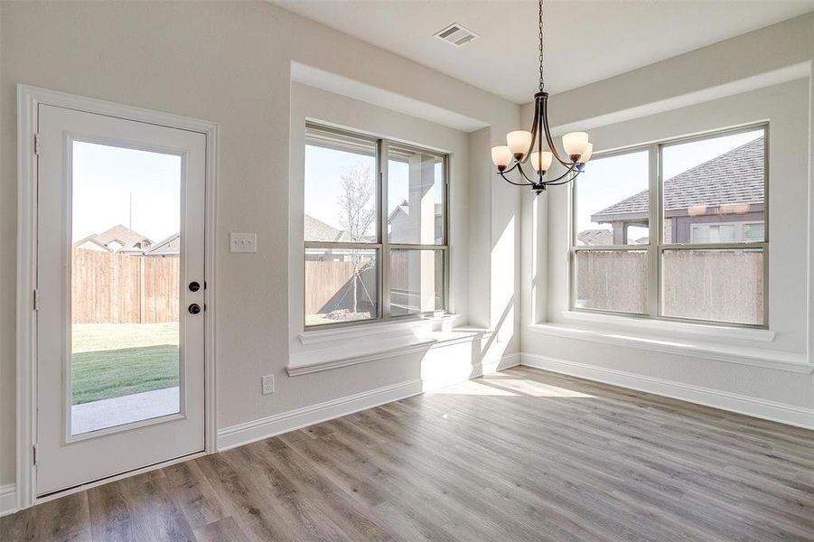 Unfurnished dining area featuring wood-type flooring and an inviting chandelier