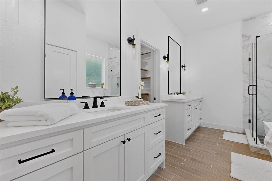 Dual vanity with white cabinetry, quartz countertops, black hardware, and framed mirrors