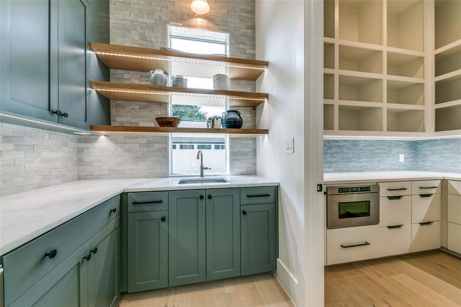 Kitchen with decorative backsplash, oven, sink, light hardwood / wood-style flooring, and green cabinetry