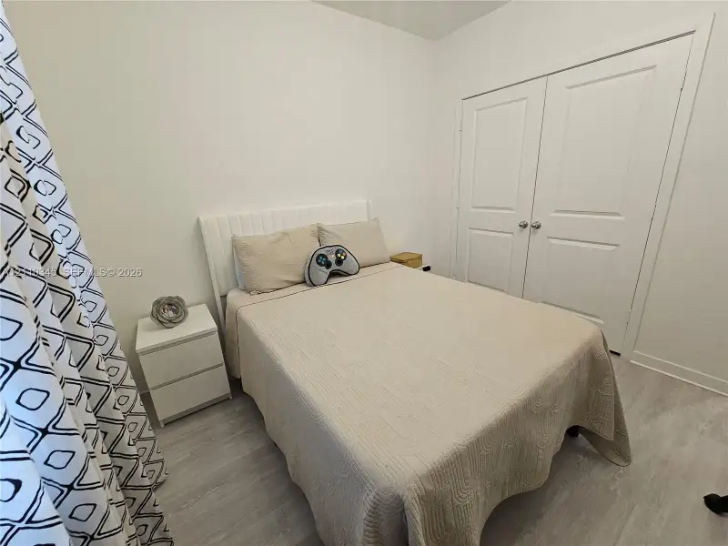Neutral interior featuring wood-finish flooring, white walls, and a double-door reach-in closet