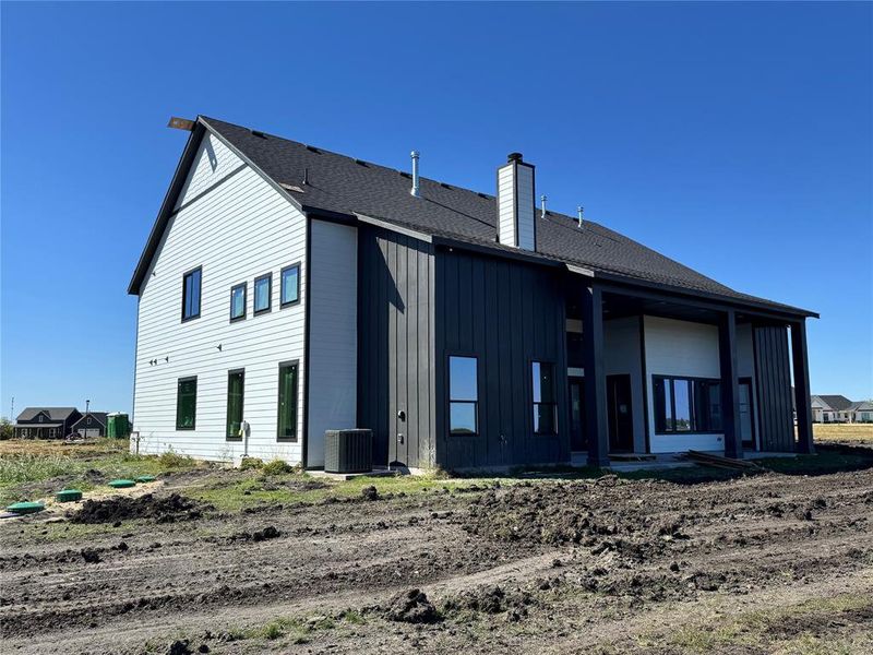 Back of house featuring board and batten siding, a patio, a chimney, and roof with shingles