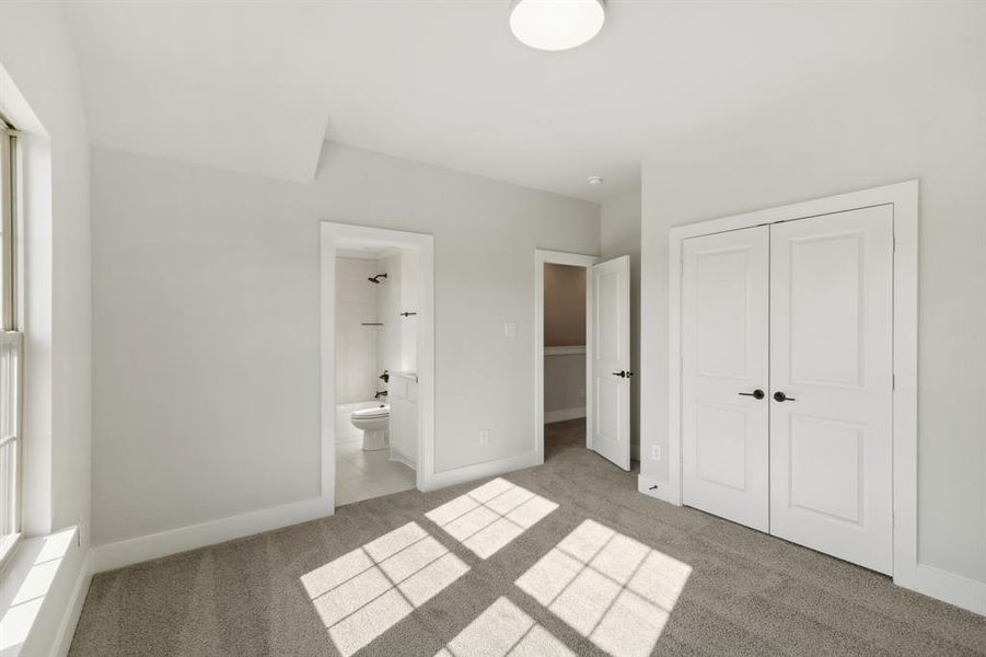 Unfurnished bedroom with ensuite bath, a closet, and carpet