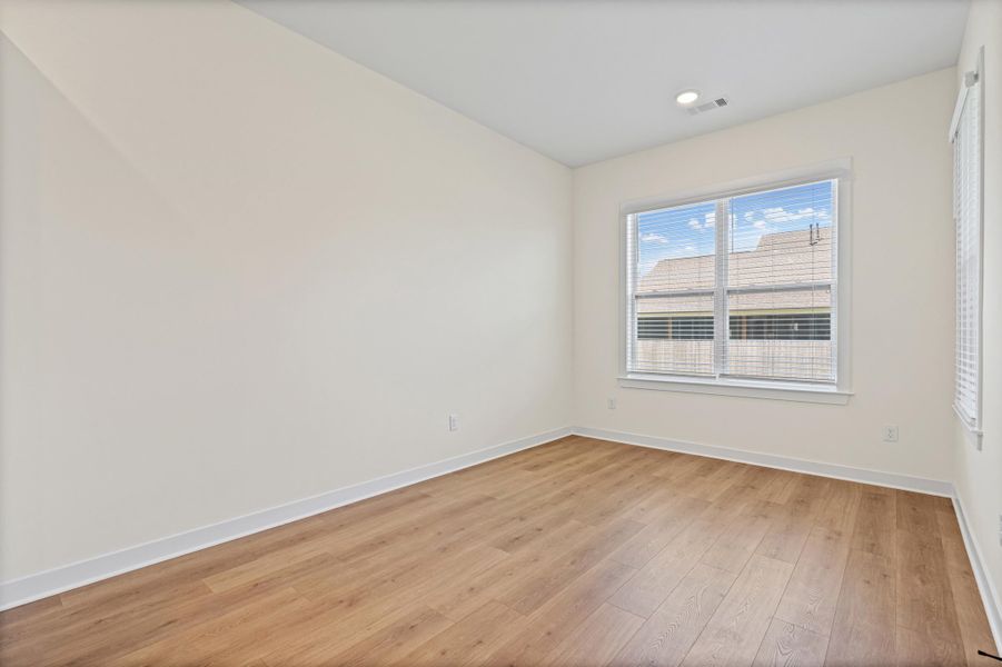 Empty room featuring wood-finish flooring, white baseboards, and light-colored walls Empty room featuring wood-finish flooring, white baseboards, and light-colored walls