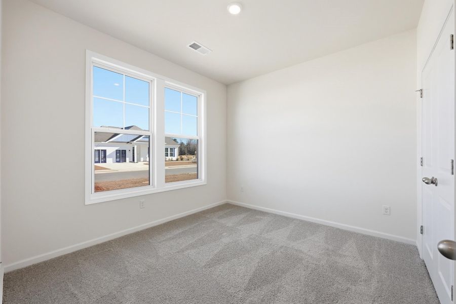 Empty room with light colored carpet and recessed lighting