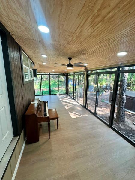 A well-lit sunroom extends living space into nature with extensive window views.