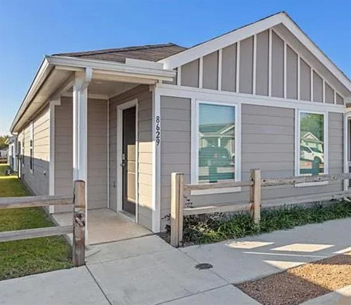 View of side of property featuring a fenced front yard, board and batten siding, and covered porch