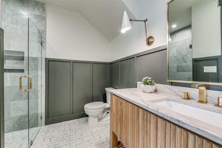 Bathroom featuring a shower with door, lofted ceiling, toilet, tile patterned floors, and vanity