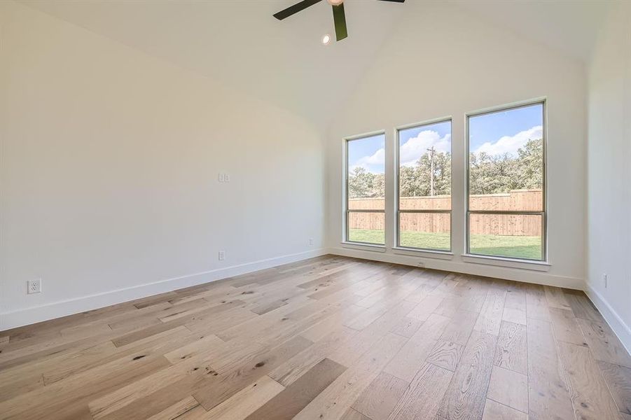 Empty room featuring ceiling fan, high vaulted ceiling, plenty of natural light, and light wood-type flooring