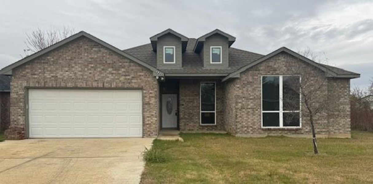 View of front of property with a garage and a front lawn