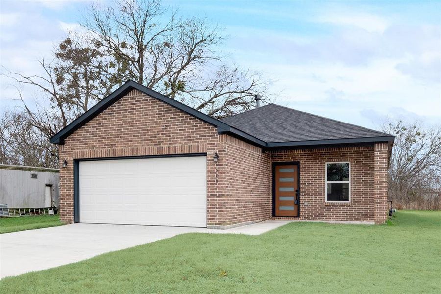 View of front facade featuring a garage and a front yard