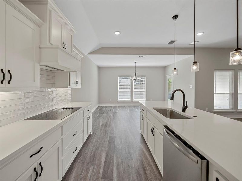 Kitchen featuring white cabinets, hanging light fixtures, dishwasher, dark wood finished floors, and black electric stovetop Kitchen featuring white cabinets, hanging light fixtures, dishwasher, dark wood finished floors, and black electric stovetop