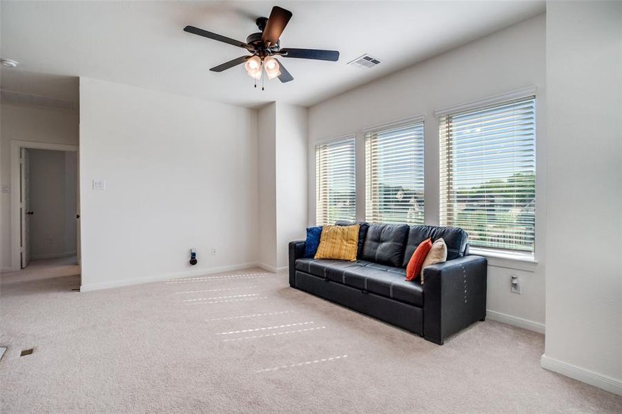 Living area featuring ceiling fan and light carpet