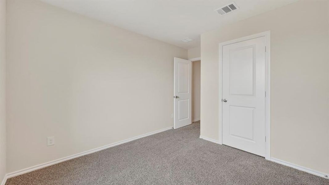 Neutral-toned interior room with gray flecked carpet and white baseboards